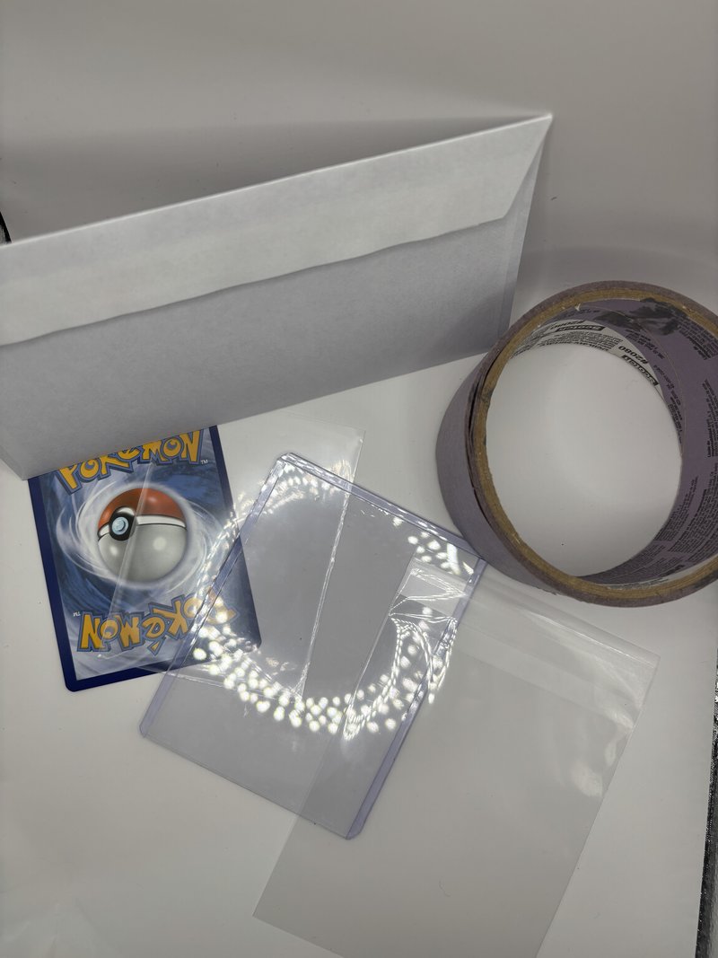 All materials laid out flat — penny sleeve, toploader, tape, envelope, and stamp